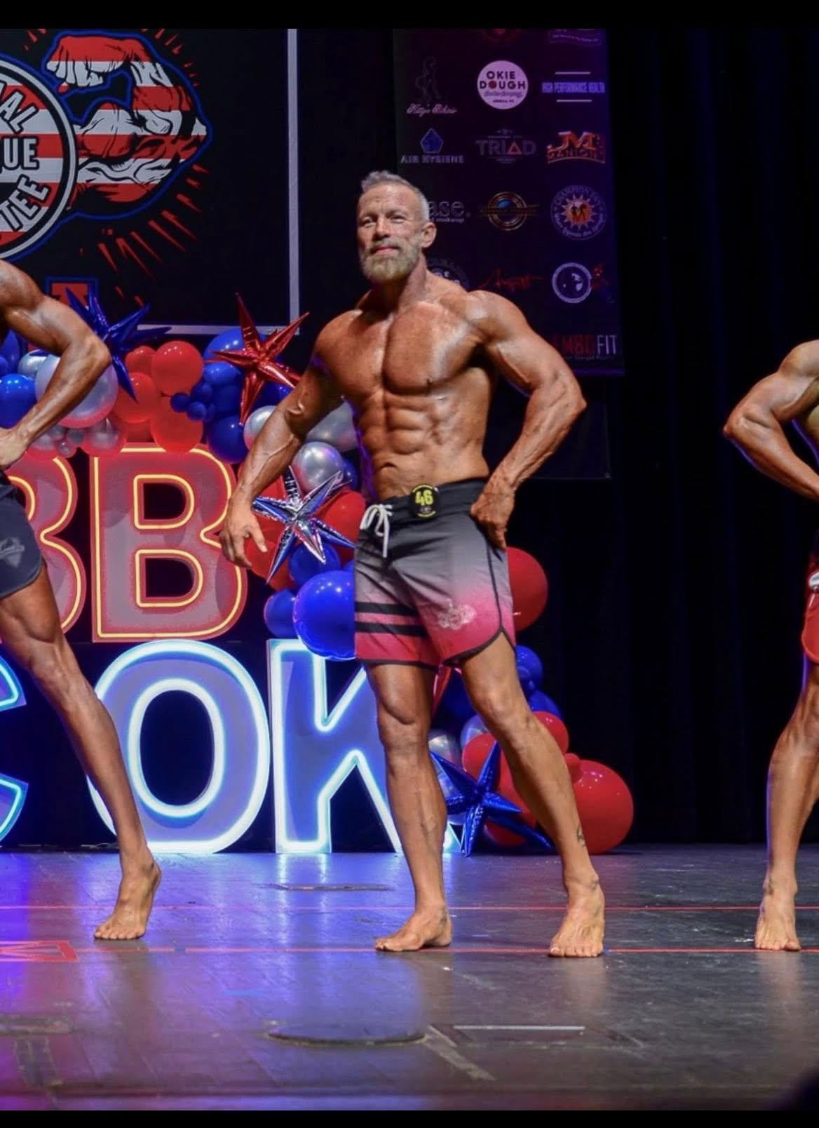 Masters physique competitor posing on the NPC Oklahoma stage in contest condition